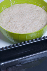 Baking bread at home. Wholemeal dough lies in a container. Near metal baking dish for bread.