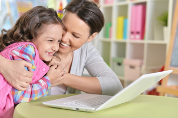 Portrait of mother and daughter using laptop