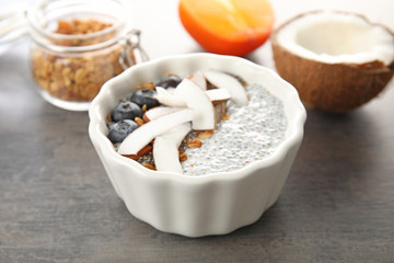 Fototapeta na wymiar Bowl of tasty chia seed pudding with coconut, granola and blueberries on table