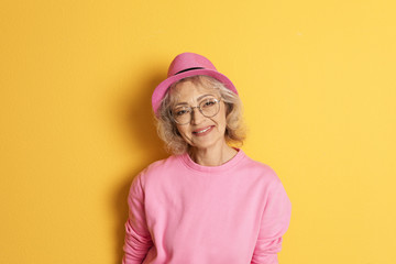 Portrait of mature woman in hipster outfit on color background