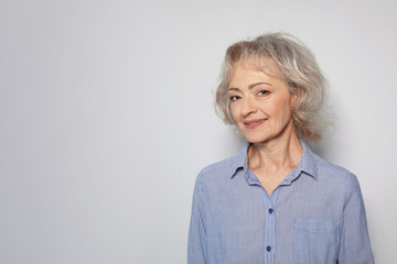 Portrait of mature woman on grey background. Space for text