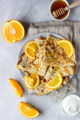 Crepes with orange, honey and natural yogurt or sour cream. Thin pancakes. Light concrete background. Copy space.