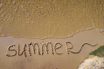 Fototapeta premium Summer written on the sea sand. Natural sandy background with beach and transparent pure wave. Place for text