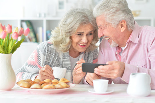 Portrait of happy senior couple looking at smartphone
