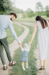 Young Happy Family. A stylish father with a beard keeps a daughter in his arms with his wife