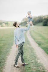Obraz premium portrait of father and child. A stylish father with a beard keeps on his arms a child, a little girl, they embrace and smile, rejoice and have fun. Happy Father's Day