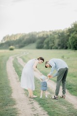 Young Happy Family. A stylish father with a beard keeps a daughter in his arms with his wife