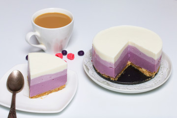 Blueberry cheesecake. A piece of ready-made dessert on a saucer. Jelly layers of different colors are visible.