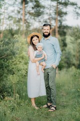 Fototapeta premium family with a child on their hands in the park looking at the camera