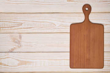 Old empty wooden  cutting board on white wooden background, top view