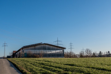 Obraz premium Strommasten hinter landwirtschaftlicher Lagerhalle