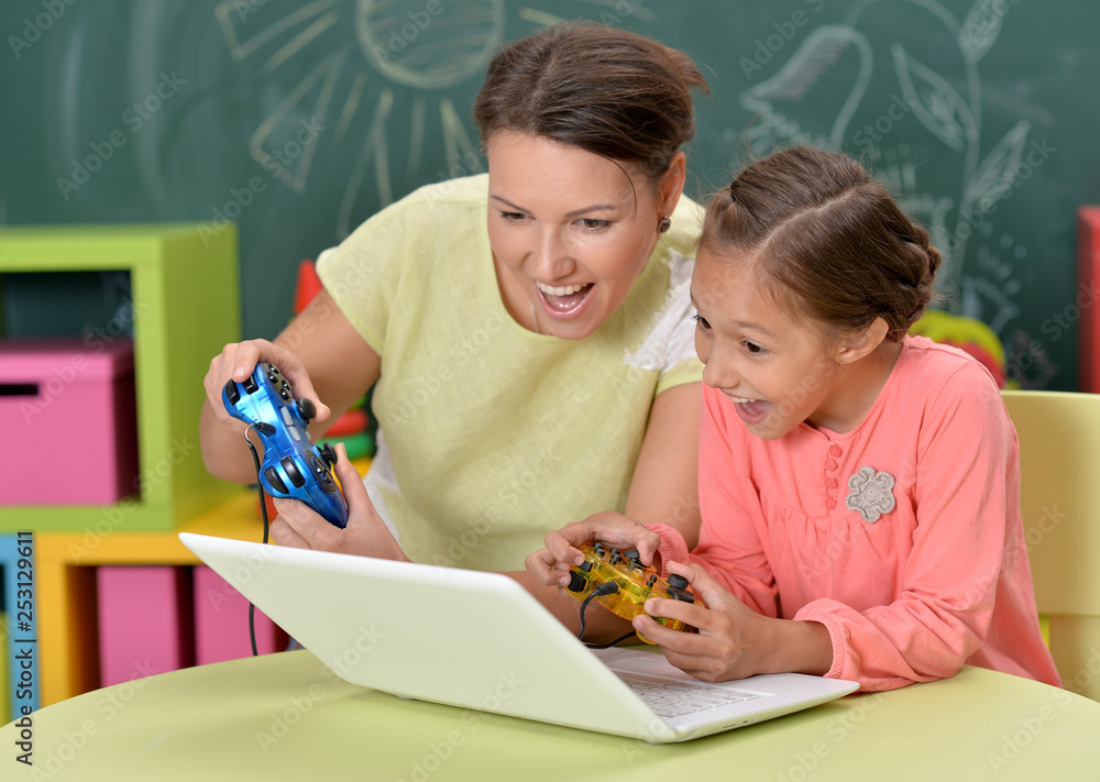 Wall mural portrait of mother with little daughter playing computer games