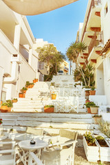 Beautiful street in Agios Nikolaos of Greece. Small street with flowers and cafes. Selective focus.