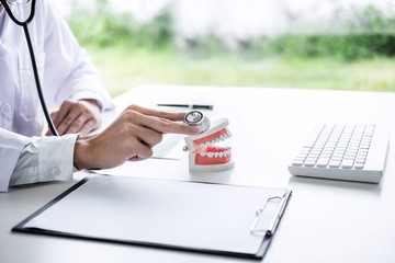 Fototapeta premium Male doctor or dentist checking teeth disease in dental model and equipment used in the treatment of dental and dentistry at workplace