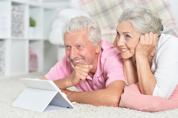 Portrait of happy senior couple using tablet at home