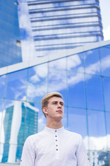 Young guy on the background of the business center building in a white shirt