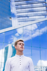 Young guy on the background of the business center building in a white shirt