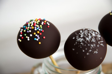 Three cake pops in a jar on a white background