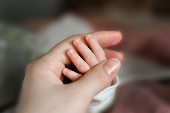 Close up baby's hand put on mom's hand. Mom nursing baby. mom and baby boy relax at home. Nursery interior. Mother breast feeding baby. Family at home. Mom's love. selected focus
