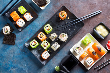Traditional Japanese food- sushi, rolls, chopsticks, soy sauce on color stone background. Sushi menu. Top view copy space
