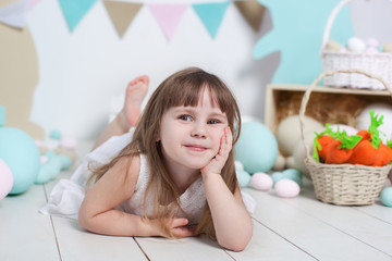 Easter 2019 Close-up portrait of a beautiful little girl's face. Many different colorful Easter eggs, colorful Easter interior. Easter bunny, carrot and colorful flags. Smiling girl
