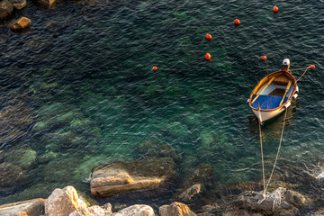 Obraz premium Solitary boat tied to a rock on the shore in the ocean sea