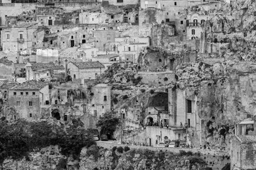 MATERA, ITALY - AUGUST 26, 2018: Tourists and local people look very small walking the narrow city streets of the ancient establishment as seen from far away the hills across in the summer afternoon
