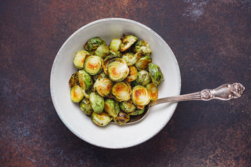 Top view of a ceramic bowl with roasted brussel sprouts on a table. The concept of healthy vegetarian eating.