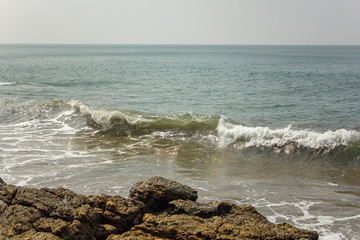 Fototapeta na wymiar rock on the background of the ocean waves and the boundless sea horizon