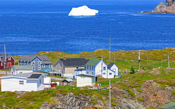 Iceberg in Harbour. Twillingate, Newfoundland, Canada. Maritime homes along the rugged cove shoreline in this coastal community, 