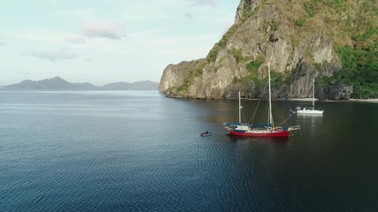 Aerial drone shot of high mountain covered with tropical forest and boats anchored in the bay. Tropical landscape. Travel concept Philippines,El Nido.