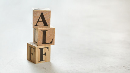 Pile with three wooden cubes - letters ALF for Always Listen First on them, space for more text / images on right side.