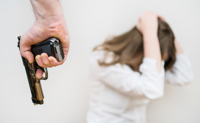 Fototapeta premium Home violence concept. Man with gun threaten woman.