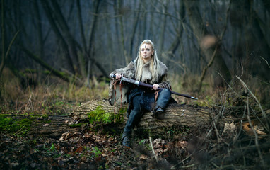 Mad furious viking woman warrior with a sword in her hands, in the woods. Authentic recreation of...