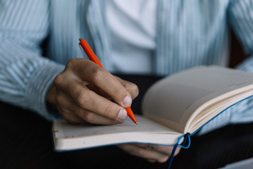 Close up of man's hand holding pen, taking notes in notebook, writing information, planning working...