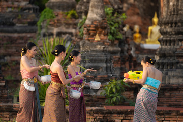 Songkran festival in Thailand. Happy Thai girls in Thailand cultural costume play water in the Thai new year festival called Songkran day.