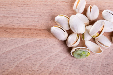 Close up Pistachio nuts with shell on wooden floor background.