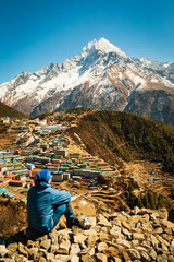 Everest trekking. The man sits and looks into the valley. Thinks and contemplates. Near the mug....