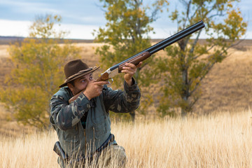 Hunter with a hat and a gun in search of prey in the steppe