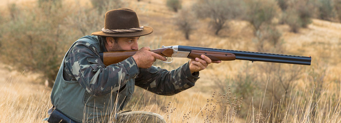 Fototapeta premium Hunter with a hat and a gun in search of prey in the steppe