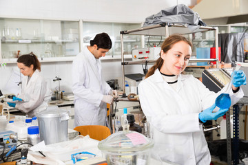 Young female lab technician working with reagents in test tubes during chemical experiment