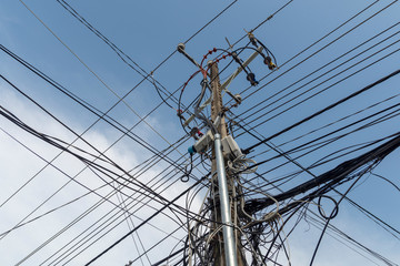 Cable chaos on a pylon against a blue sky.