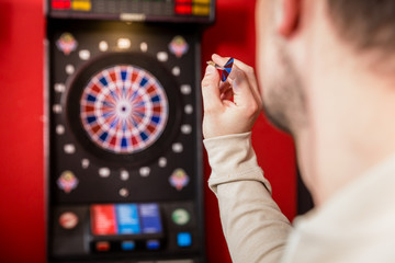 Man aiming against dartboard