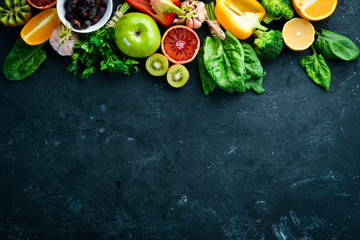 Healthy vegetarian food: Orange, lemon, apple, rose, garlic, broccoli, apple, kiwi, spinach. Top view. free space for your text.