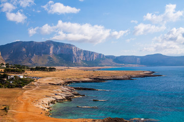 Beautiful postcard view of the Sicilian rocky coastline in Italy, summer travel in Europe, sea and clouds in the blue sky