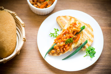 fried bread toasts with stewed beans and vegetables in a plate