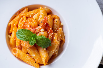 Penne pasta with shrimps, tomato sauce on white plate . close up ,top view