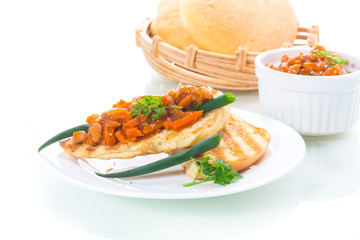 fried bread toasts with stewed beans and vegetables in a plate