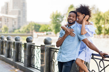 Loving young african-american couple embracing on bridge