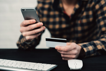 Cropped picture of man with credit card white pattern and phone